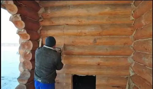 લાકડાના ઘરમાં પ્રવેશ દ્વારને સ્થાપિત કરી રહ્યા છે