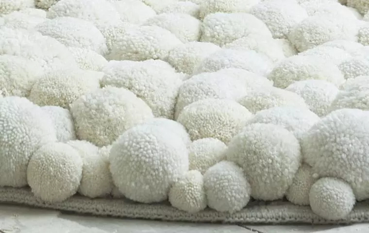Білий килимок з помпонами