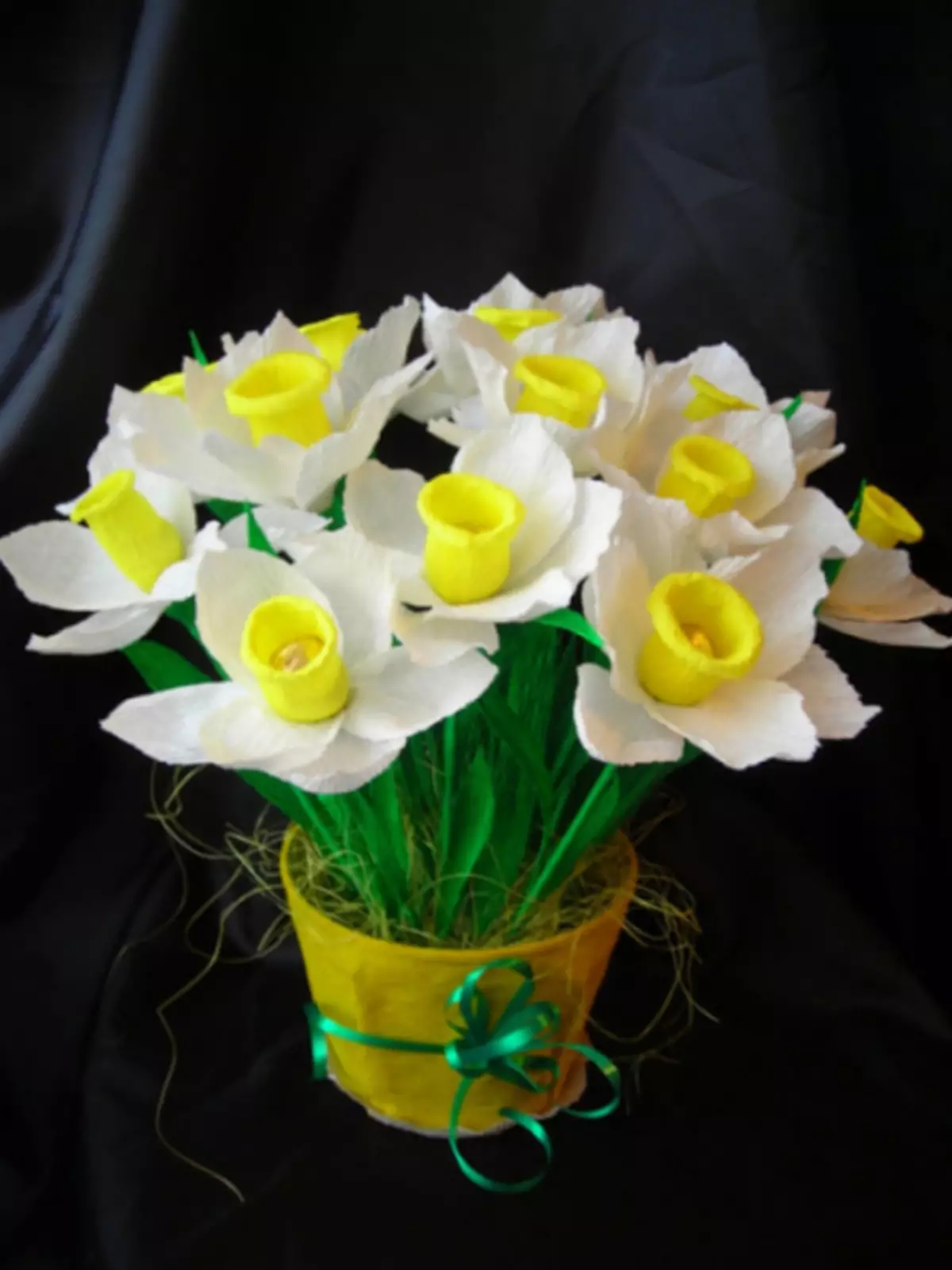 Narcissus kuchokera papepala lotetezedwa ndi manja awo omwe ali ndi maswiti